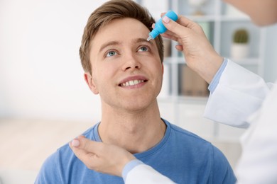 Photo of Ophthalmologist applying medical drops onto patient's eye in clinic, closeup