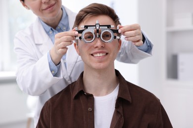 Photo of Ophthalmologist examining patient's vision with trial frame in clinic, closeup