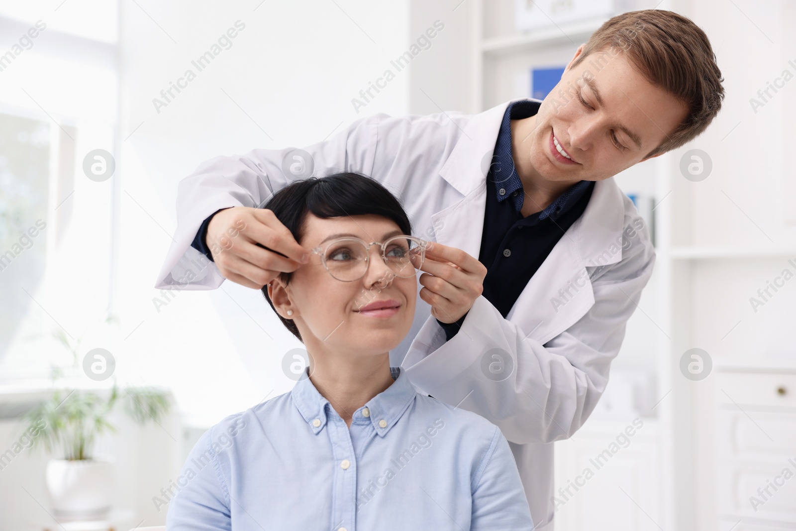 Photo of Ophthalmologist giving glasses to patient in clinic