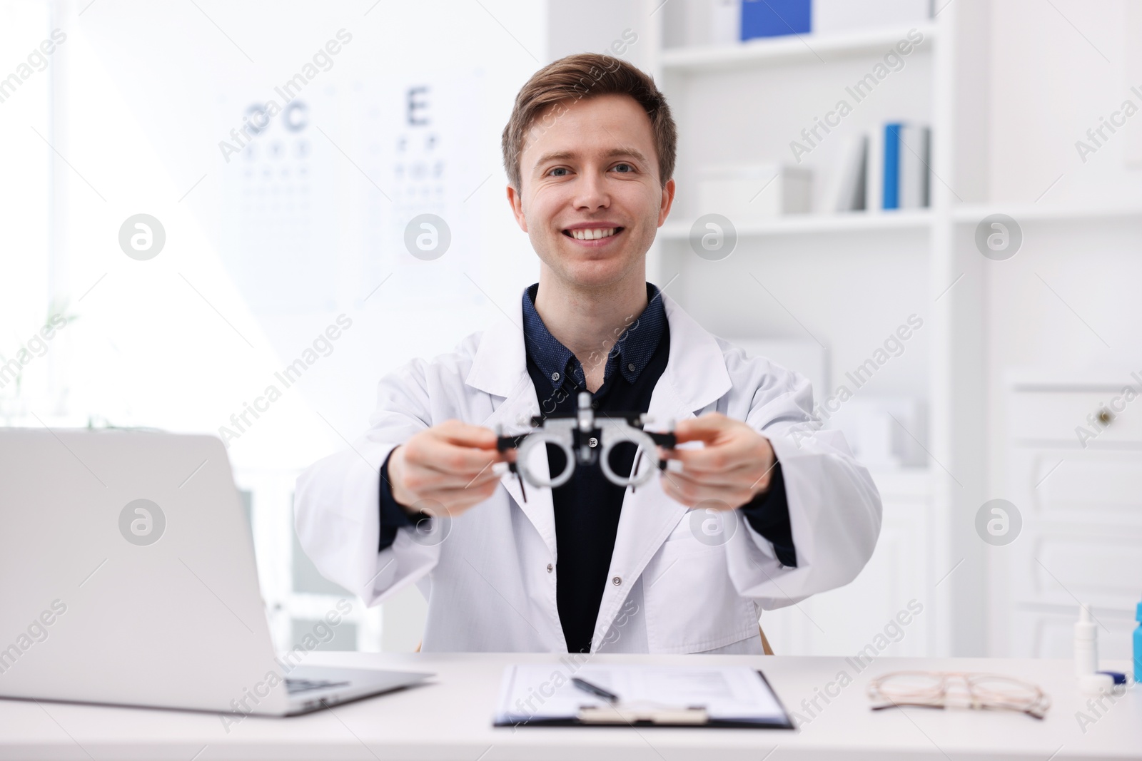 Photo of Portrait of professional ophthalmologist with trial frame at white table in clinic