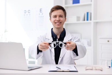 Photo of Portrait of professional ophthalmologist with trial frame at white table in clinic