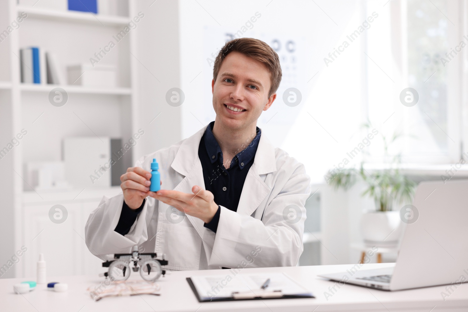 Portrait of professional ophthalmologist with eye drops at white table in clinic Photo of Portrait of professional ophthalmologist with eye drops at white table in clinic