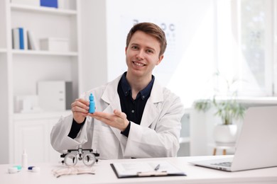 Photo of Portrait of professional ophthalmologist with eye drops at white table in clinic