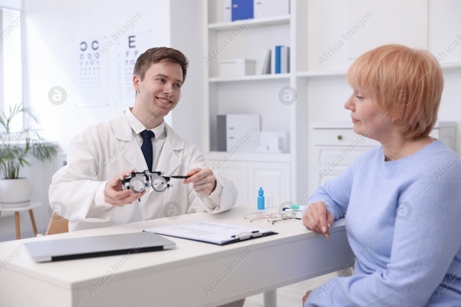 Ophthalmologist consulting senior woman at white table in clinic Photo of Ophthalmologist consulting senior woman at white table in clinic