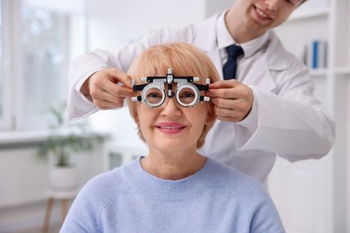 Photo of Ophthalmologist examining patient's vision with trial frame in clinic