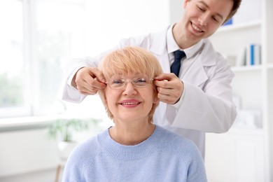 Photo of Ophthalmologist giving glasses to patient in clinic, closeup