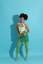 Photo of Fashionable portrait of beautiful Brazilian woman in stylish outfit on light blue background