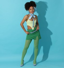 Photo of Fashionable portrait of beautiful Brazilian woman in stylish outfit on light blue background