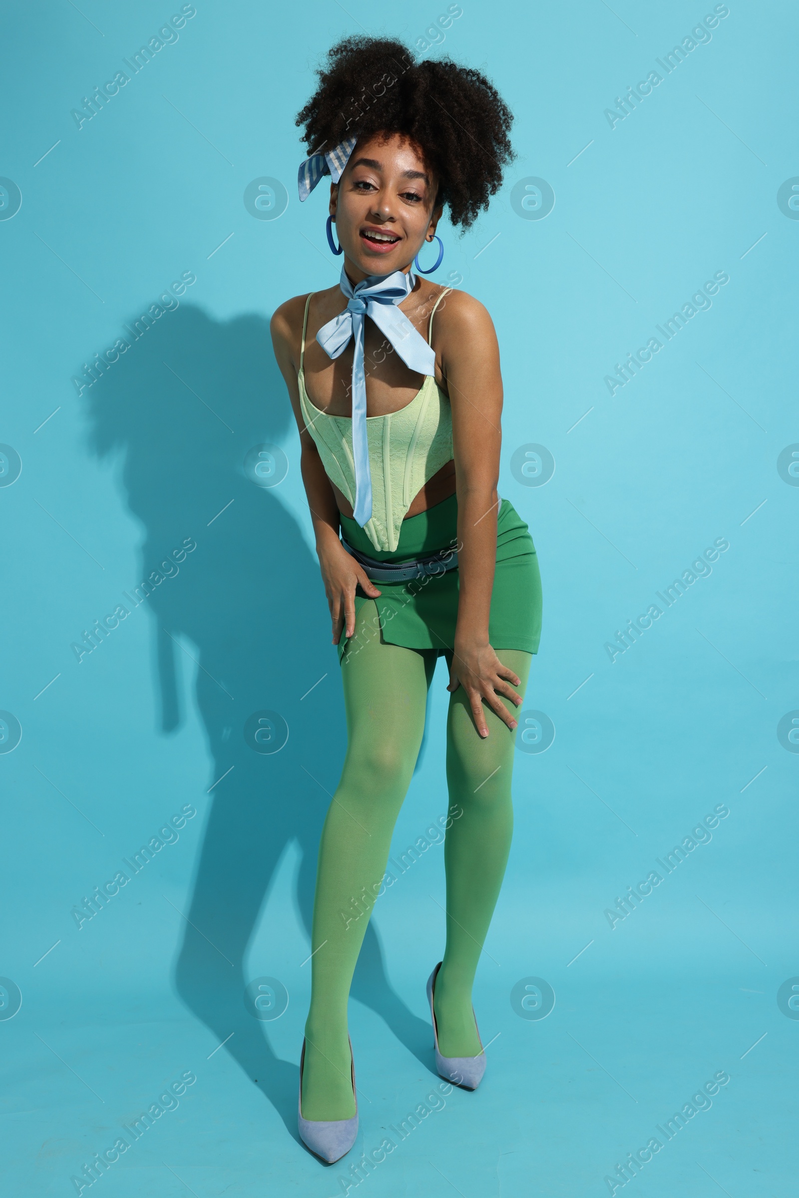 Fashionable portrait of beautiful Brazilian woman in stylish outfit on light blue background Photo of Fashionable portrait of beautiful Brazilian woman in stylish outfit on light blue background