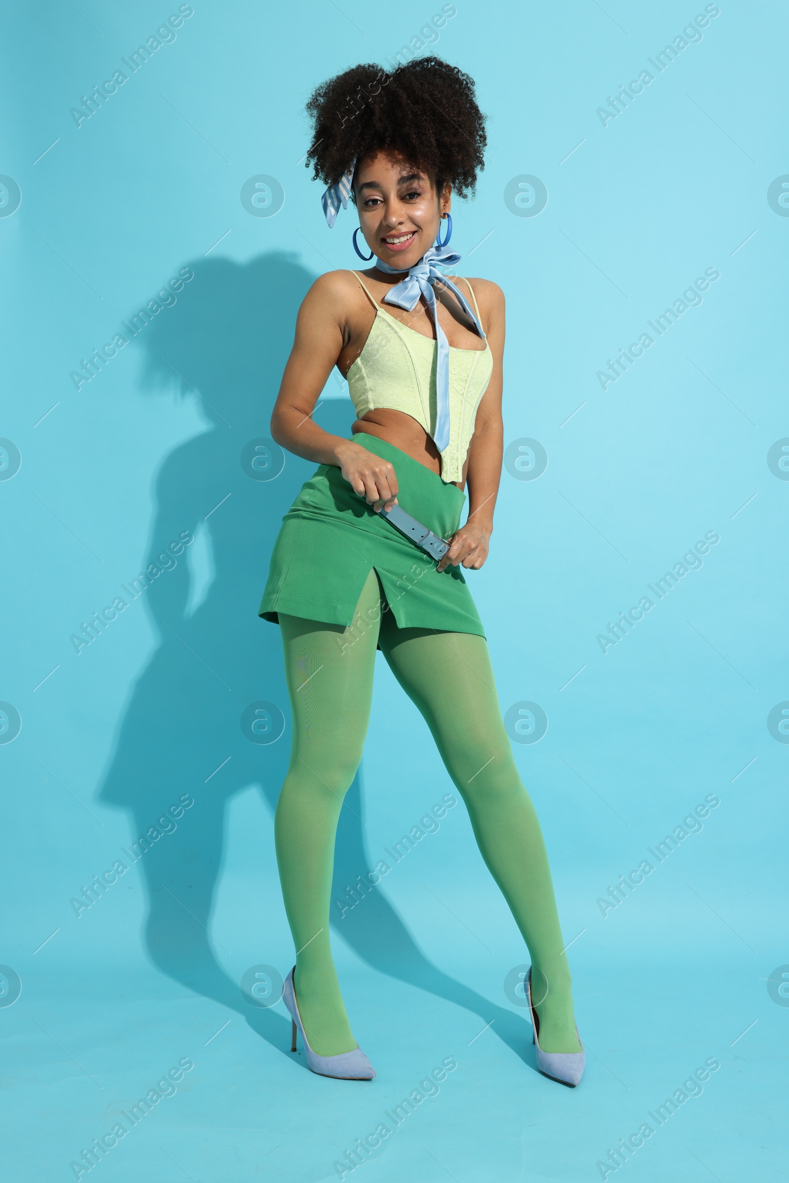 Fashionable portrait of beautiful Brazilian woman in stylish outfit on light blue background Photo of Fashionable portrait of beautiful Brazilian woman in stylish outfit on light blue background