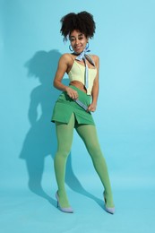 Photo of Fashionable portrait of beautiful Brazilian woman in stylish outfit on light blue background