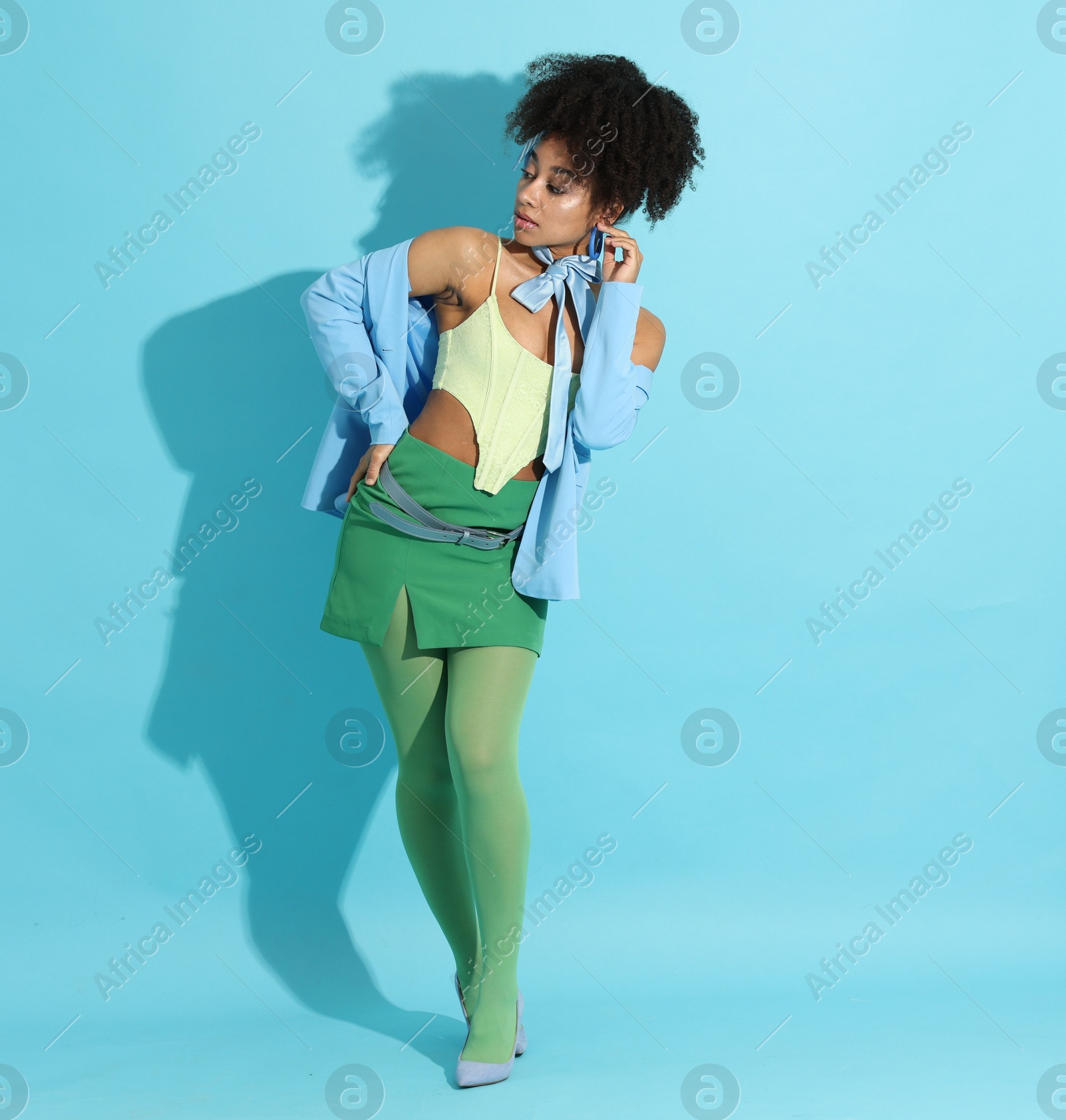 Fashionable portrait of beautiful Brazilian woman in stylish outfit on light blue background Photo of Fashionable portrait of beautiful Brazilian woman in stylish outfit on light blue background
