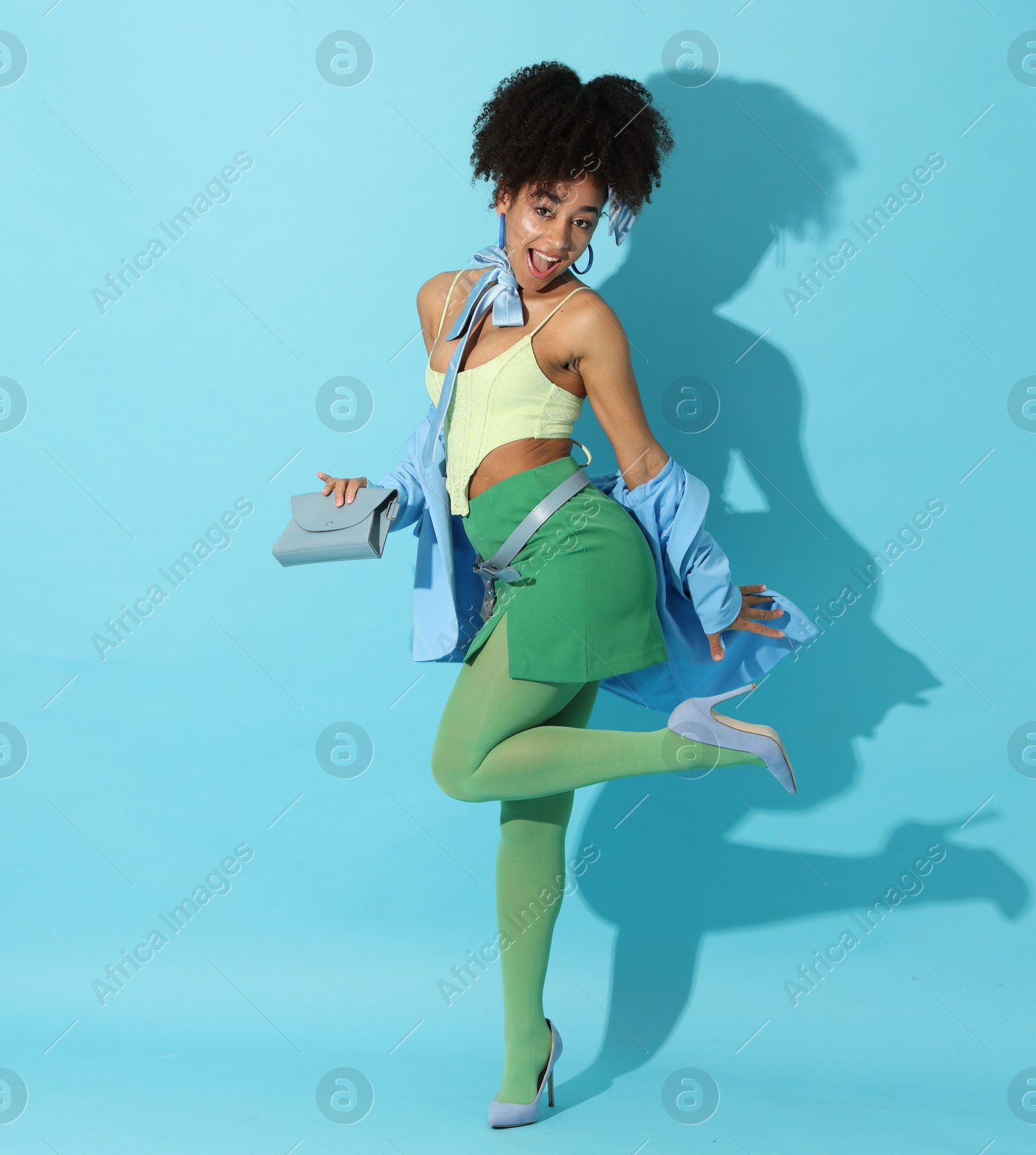 Fashionable portrait of beautiful Brazilian woman in stylish outfit on light blue background Photo of Fashionable portrait of beautiful Brazilian woman in stylish outfit on light blue background