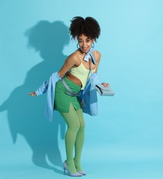 Photo of Fashionable portrait of beautiful Brazilian woman in stylish outfit on light blue background