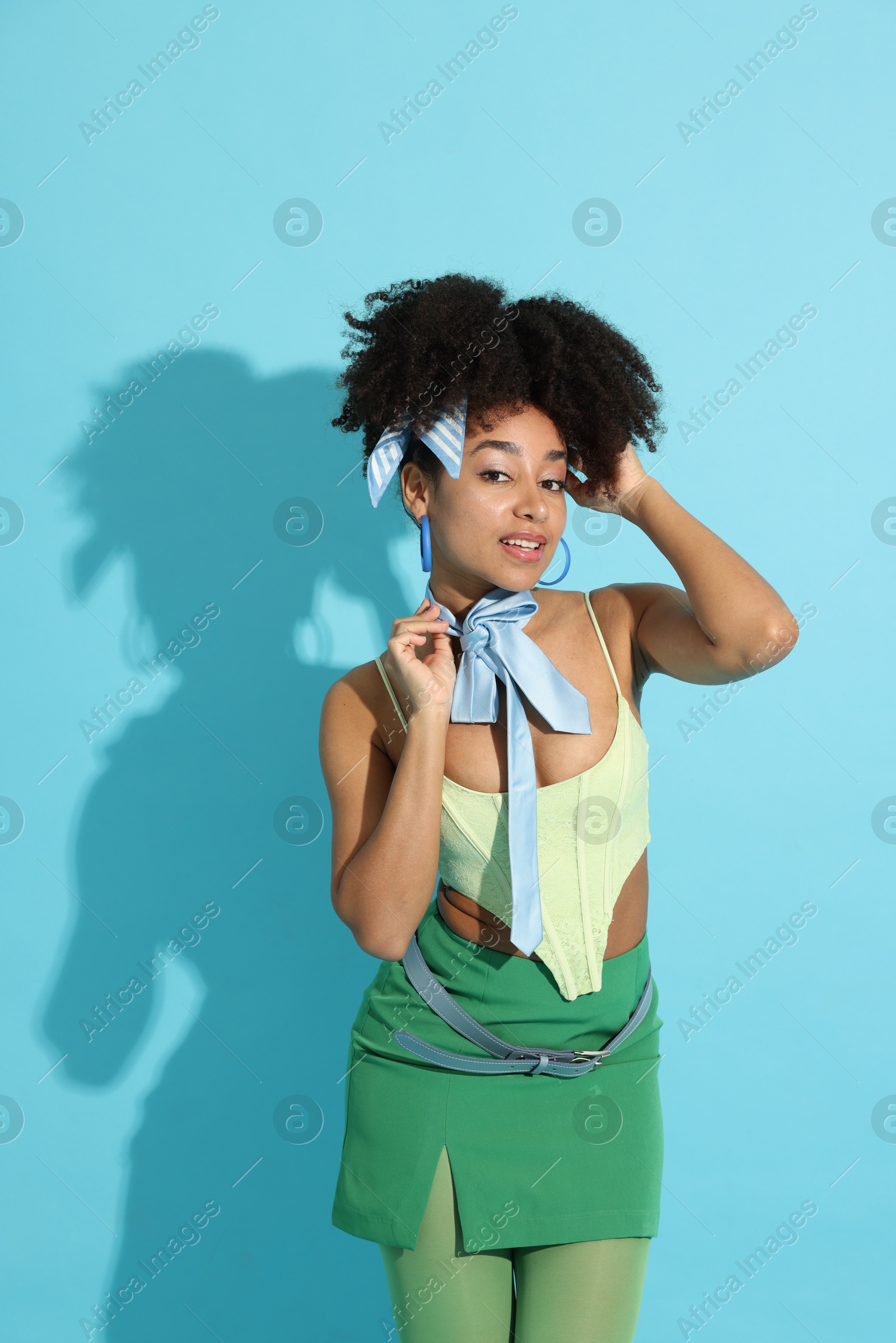 Fashionable portrait of beautiful Brazilian woman in stylish outfit on light blue background Photo of Fashionable portrait of beautiful Brazilian woman in stylish outfit on light blue background