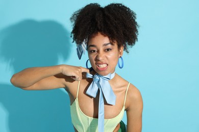 Photo of Fashionable portrait of beautiful Brazilian woman in stylish outfit on light blue background