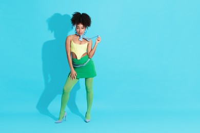 Photo of Fashionable portrait of beautiful Brazilian woman in stylish outfit on light blue background