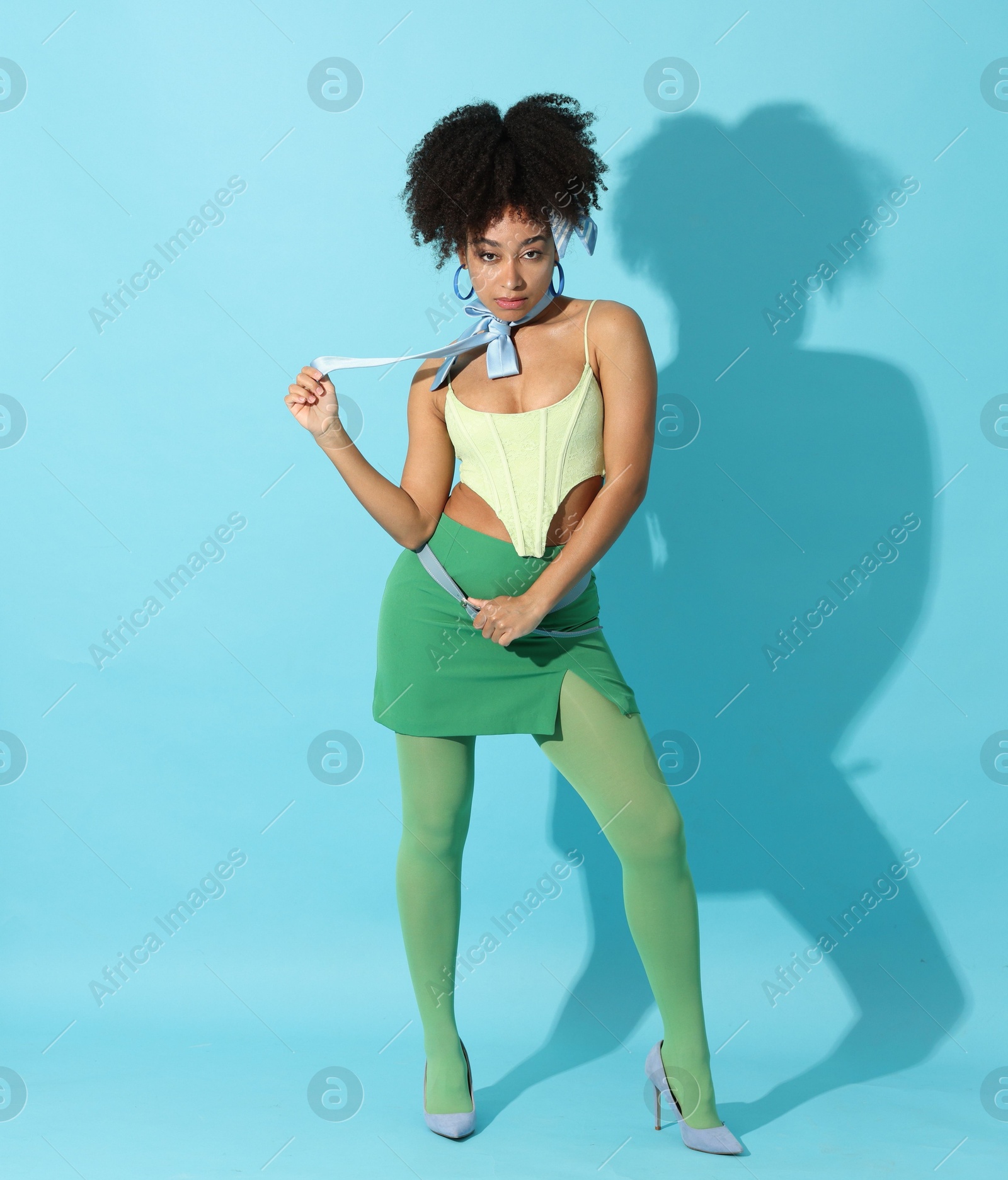 Fashionable portrait of beautiful Brazilian woman in stylish outfit on light blue background Photo of Fashionable portrait of beautiful Brazilian woman in stylish outfit on light blue background