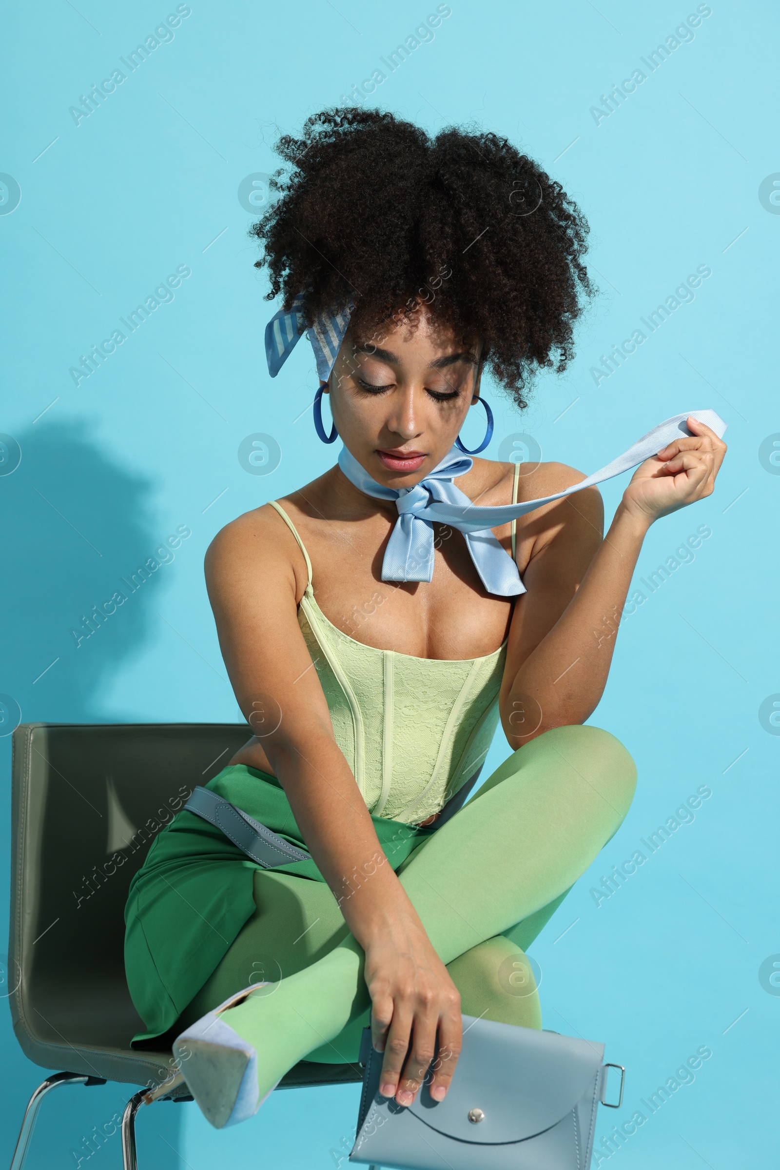 Fashionable portrait of beautiful Brazilian woman in stylish outfit on light blue background Photo of Fashionable portrait of beautiful Brazilian woman in stylish outfit on light blue background