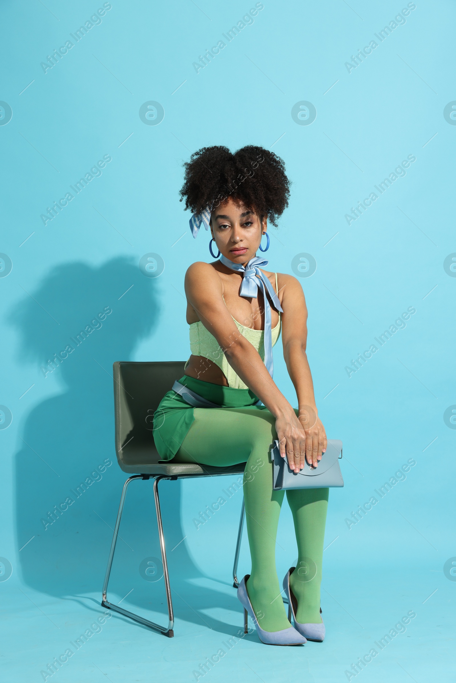 Fashionable portrait of beautiful Brazilian woman in stylish outfit on light blue background Photo of Fashionable portrait of beautiful Brazilian woman in stylish outfit on light blue background