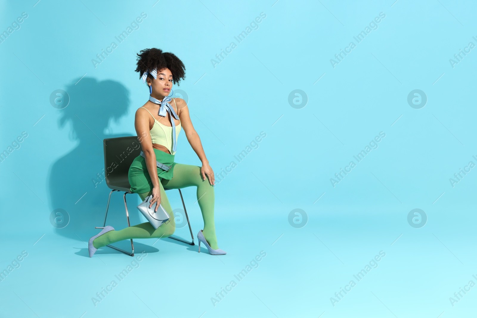 Fashionable portrait of beautiful Brazilian woman in stylish outfit on light blue background. Space for text Photo of Fashionable portrait of beautiful Brazilian woman in stylish outfit on light blue background. Space for text