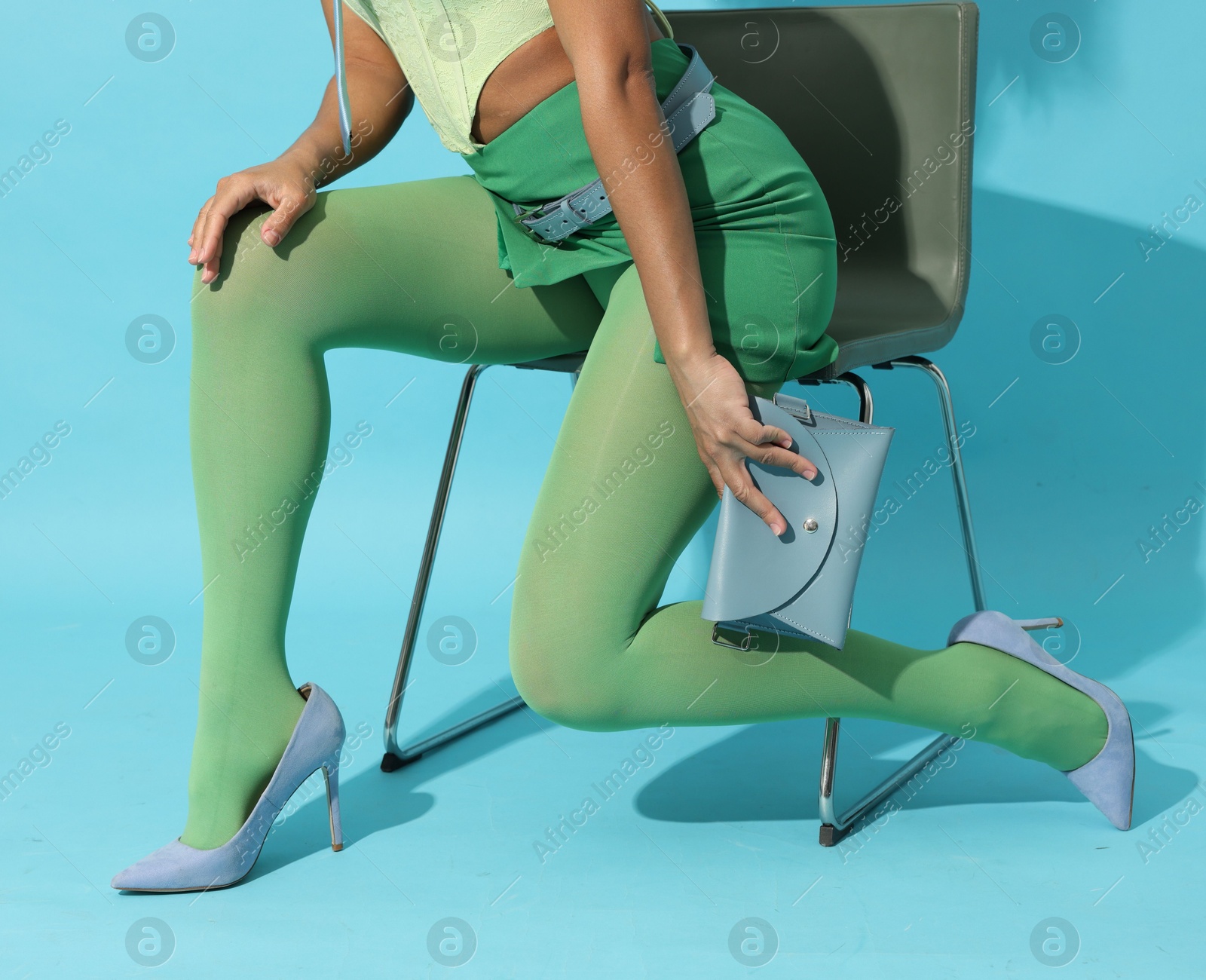 Brazilian woman in stylish outfit on light blue background, closeup. Fashion model Photo of Brazilian woman in stylish outfit on light blue background, closeup. Fashion model