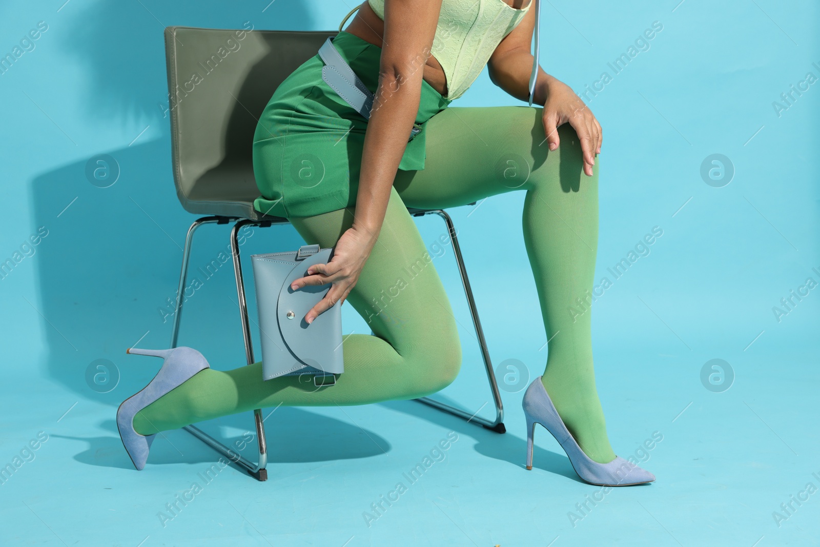 Brazilian woman in stylish outfit on light blue background, closeup. Fashion model Photo of Brazilian woman in stylish outfit on light blue background, closeup. Fashion model