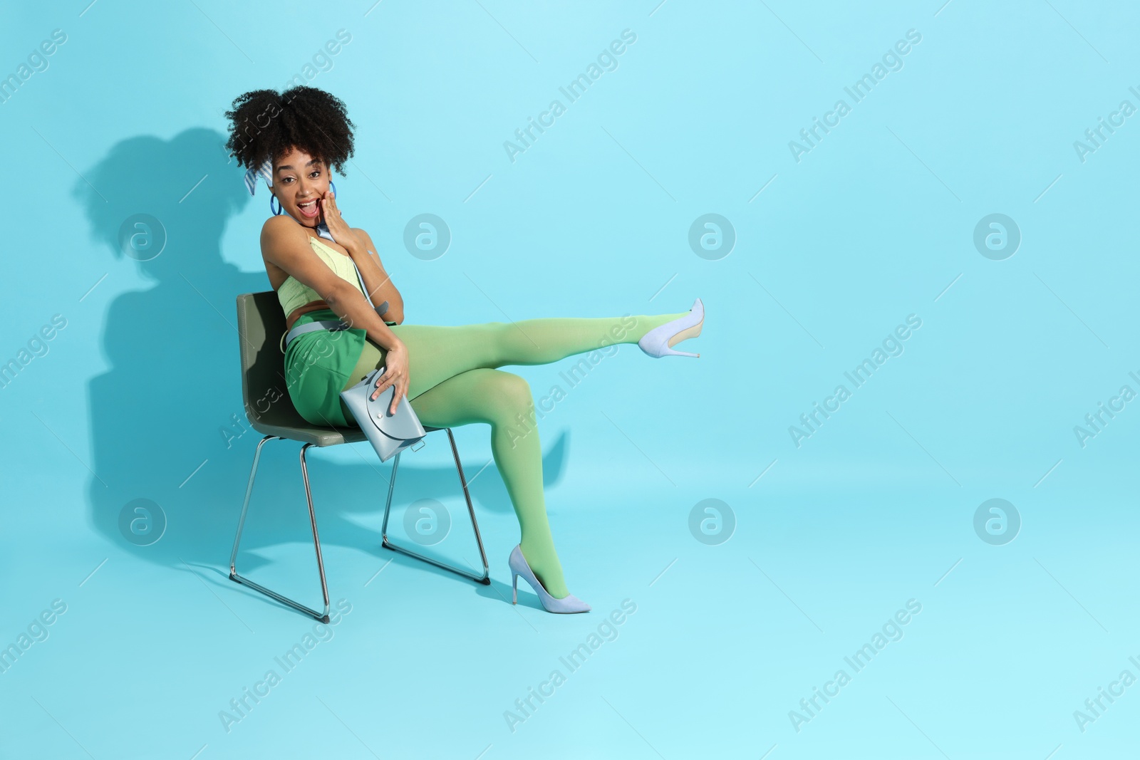Fashionable portrait of beautiful Brazilian woman in stylish outfit on light blue background. Space for text Photo of Fashionable portrait of beautiful Brazilian woman in stylish outfit on light blue background. Space for text