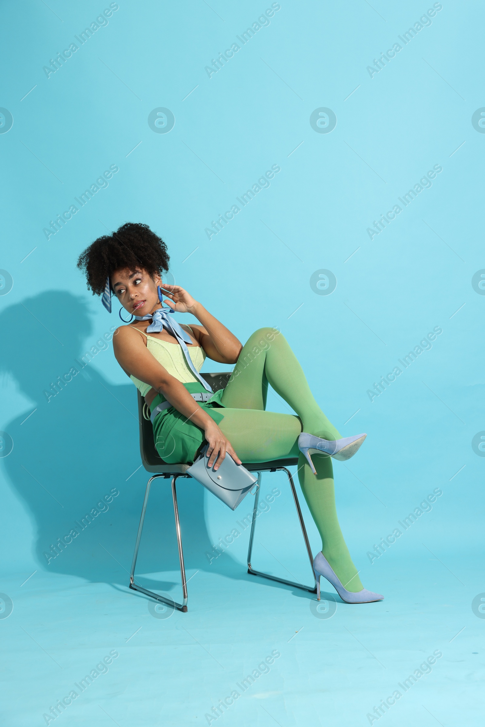 Fashionable portrait of beautiful Brazilian woman in stylish outfit on light blue background Photo of Fashionable portrait of beautiful Brazilian woman in stylish outfit on light blue background