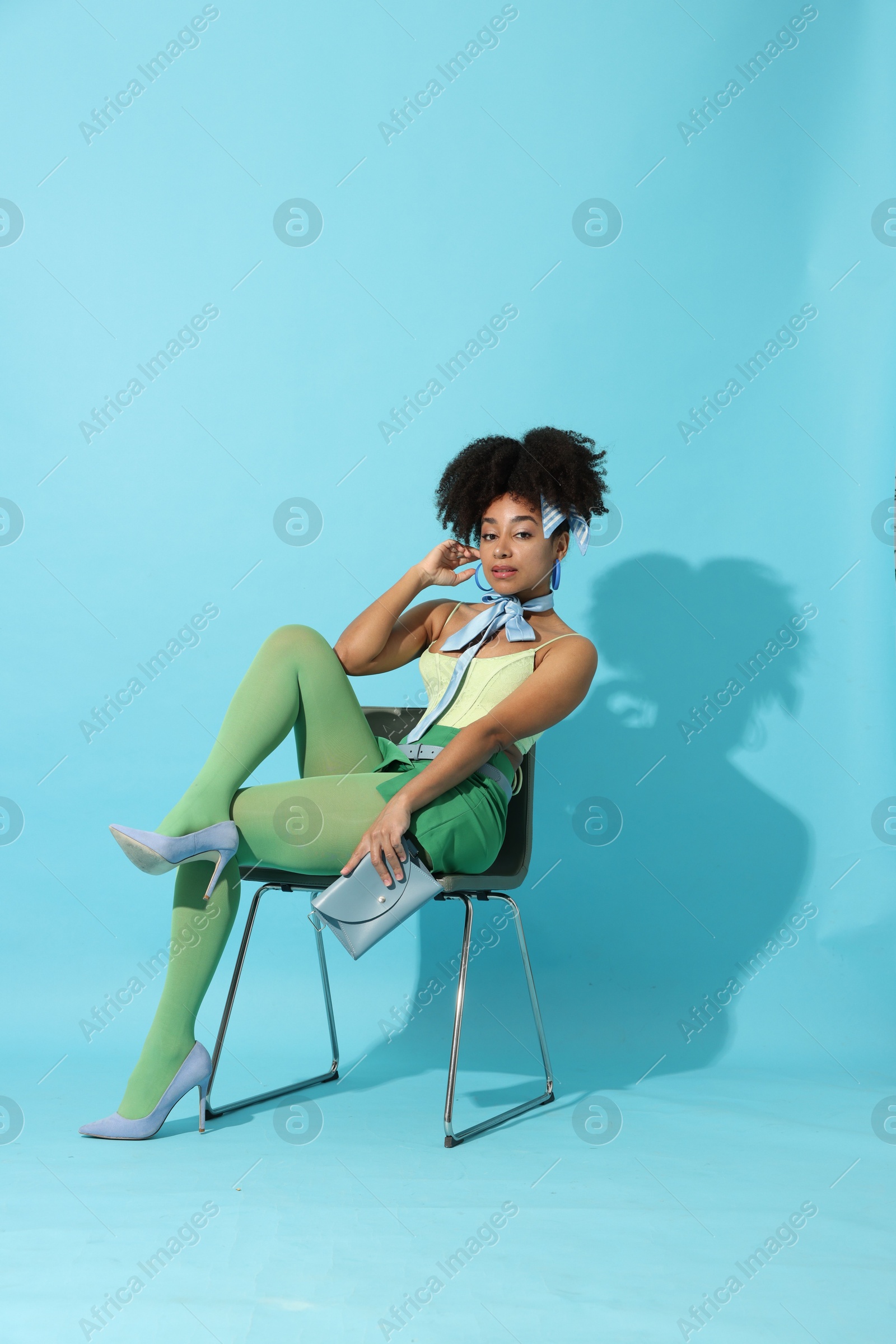 Fashionable portrait of beautiful Brazilian woman in stylish outfit on light blue background Photo of Fashionable portrait of beautiful Brazilian woman in stylish outfit on light blue background