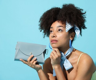 Photo of Beautiful Brazilian woman with stylish accessories on light blue background. Fashion model