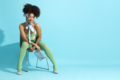 Photo of Fashionable portrait of beautiful Brazilian woman in stylish outfit on light blue background. Space for text