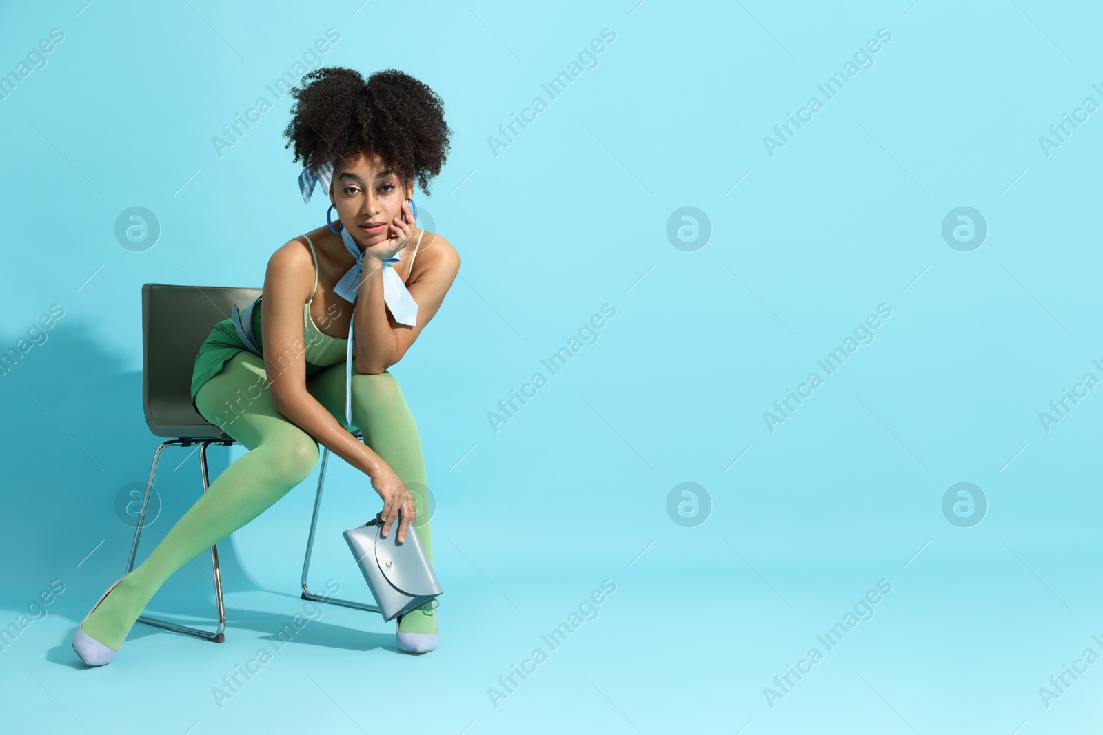 Fashionable portrait of beautiful Brazilian woman in stylish outfit on light blue background. Space for text Photo of Fashionable portrait of beautiful Brazilian woman in stylish outfit on light blue background. Space for text