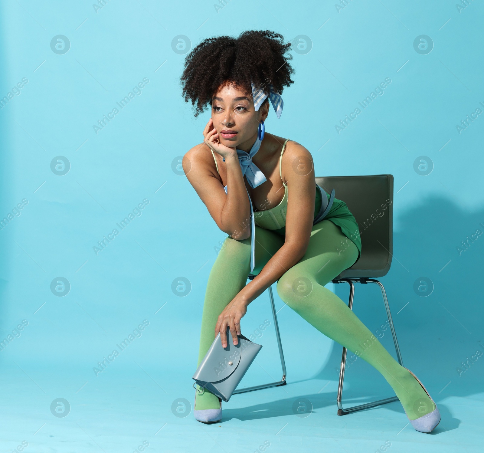 Fashionable portrait of beautiful Brazilian woman in stylish outfit on light blue background Photo of Fashionable portrait of beautiful Brazilian woman in stylish outfit on light blue background