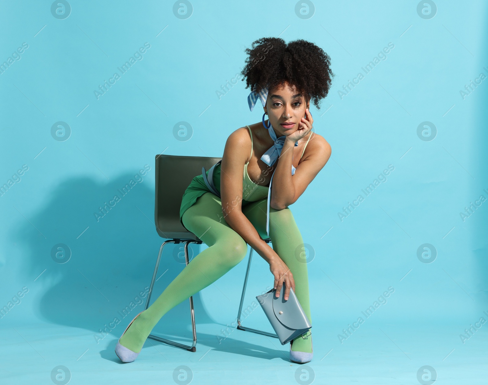 Fashionable portrait of beautiful Brazilian woman in stylish outfit on light blue background Photo of Fashionable portrait of beautiful Brazilian woman in stylish outfit on light blue background