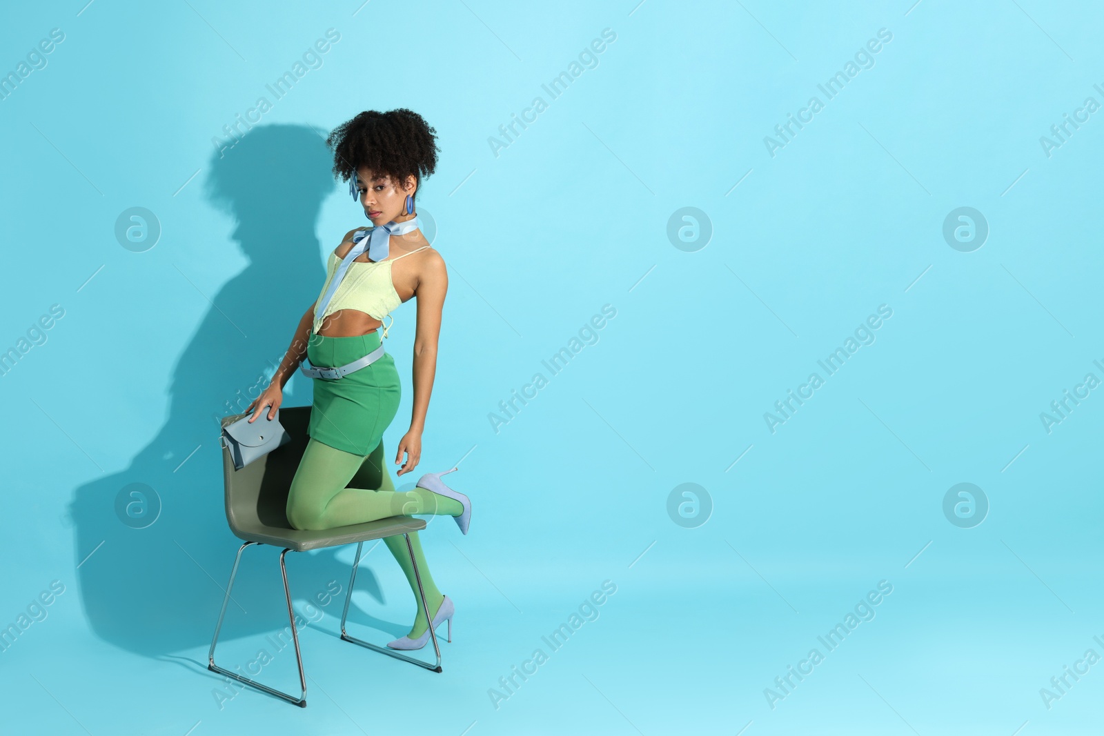 Fashionable portrait of beautiful Brazilian woman in stylish outfit on light blue background. Space for text Photo of Fashionable portrait of beautiful Brazilian woman in stylish outfit on light blue background. Space for text
