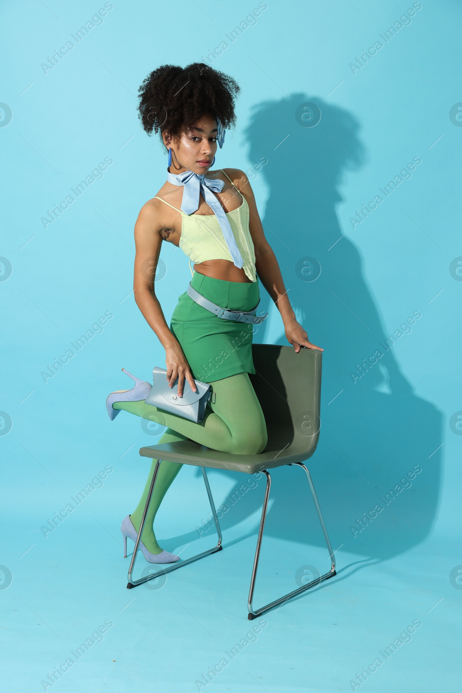 Fashionable portrait of beautiful Brazilian woman in stylish outfit on light blue background Photo of Fashionable portrait of beautiful Brazilian woman in stylish outfit on light blue background