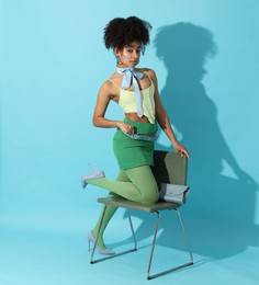 Photo of Fashionable portrait of beautiful Brazilian woman in stylish outfit on light blue background