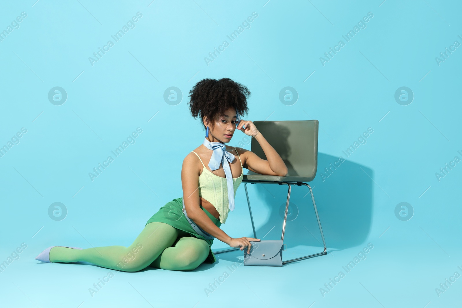 Fashionable portrait of beautiful Brazilian woman in stylish outfit on light blue background Photo of Fashionable portrait of beautiful Brazilian woman in stylish outfit on light blue background