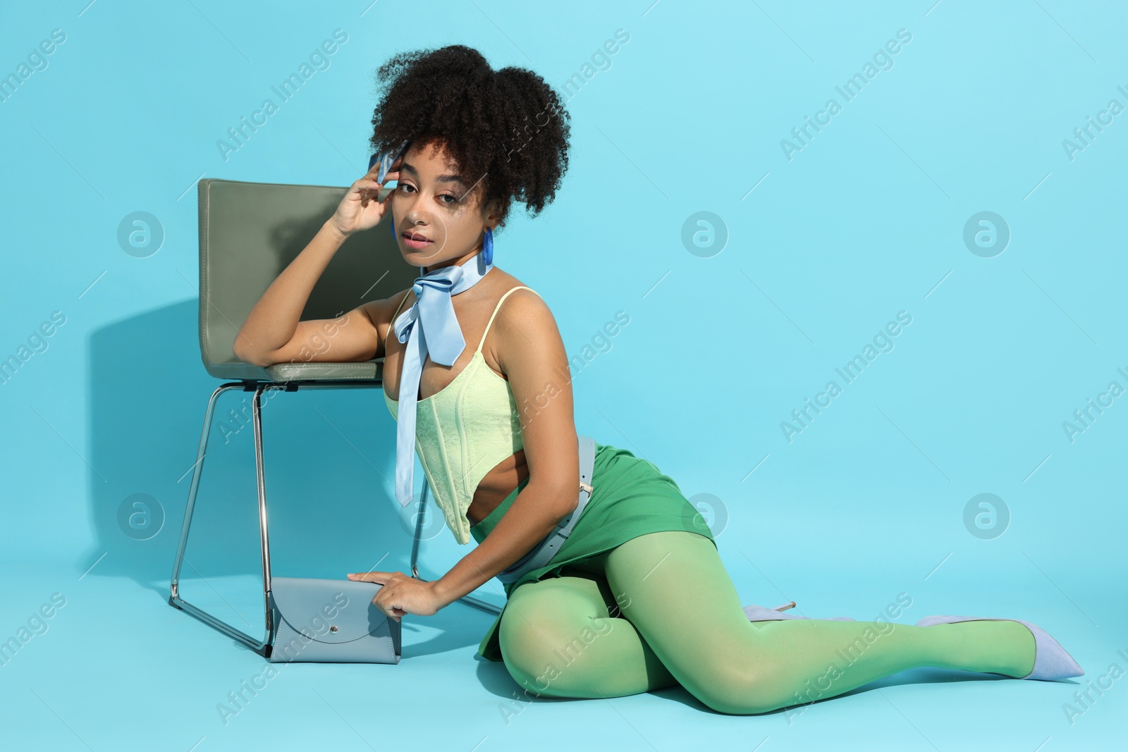 Fashionable portrait of beautiful Brazilian woman in stylish outfit on light blue background Photo of Fashionable portrait of beautiful Brazilian woman in stylish outfit on light blue background
