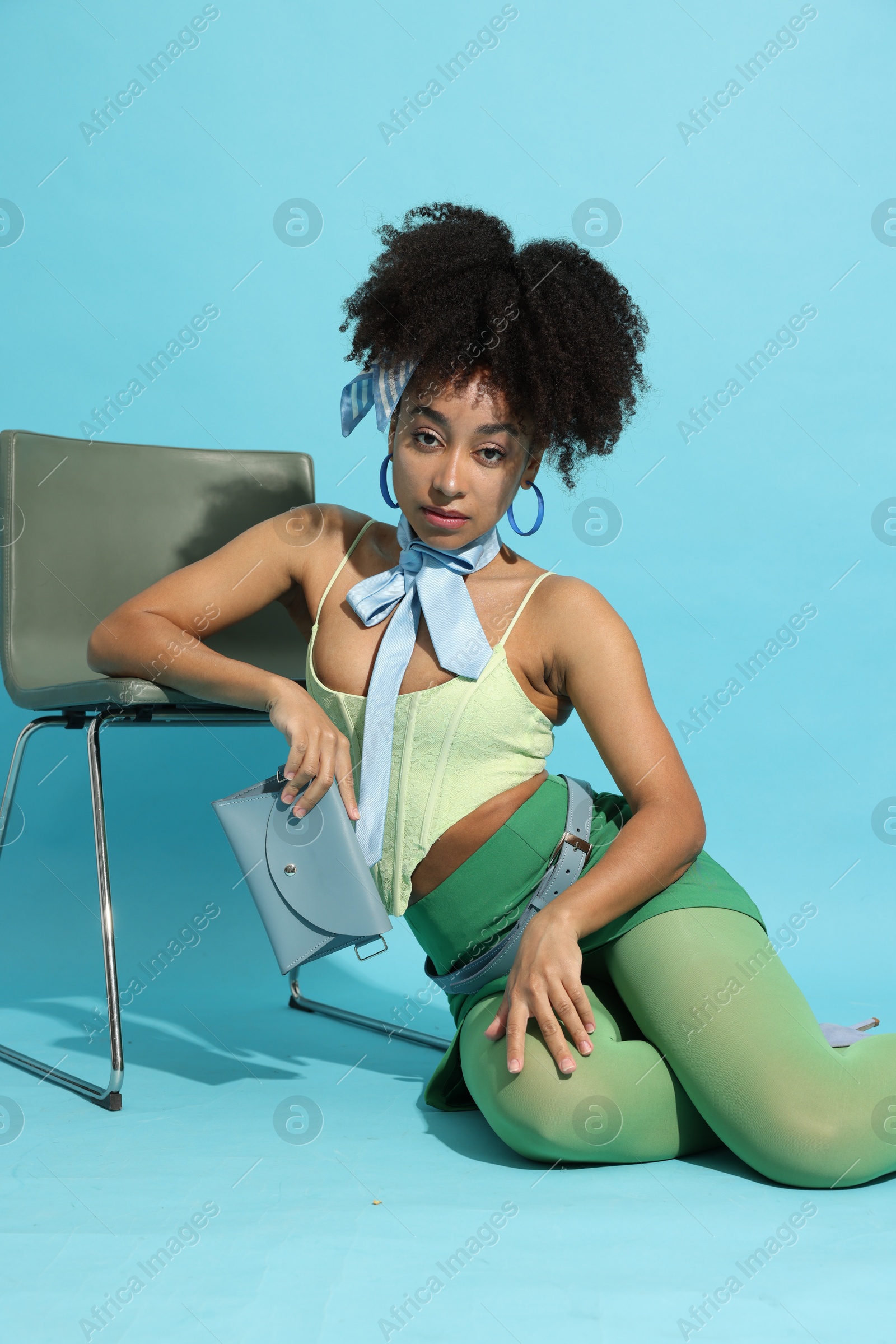Fashionable portrait of beautiful Brazilian woman in stylish outfit on light blue background Photo of Fashionable portrait of beautiful Brazilian woman in stylish outfit on light blue background