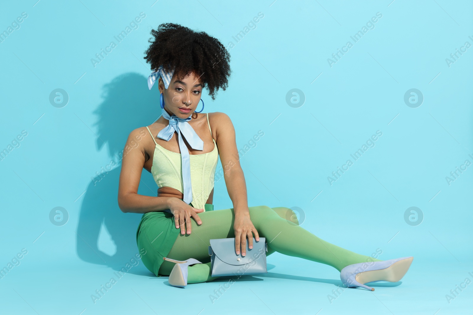 Fashionable portrait of beautiful Brazilian woman in stylish outfit on light blue background Photo of Fashionable portrait of beautiful Brazilian woman in stylish outfit on light blue background