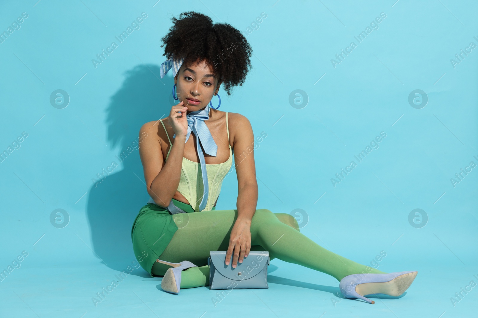 Fashionable portrait of beautiful Brazilian woman in stylish outfit on light blue background Photo of Fashionable portrait of beautiful Brazilian woman in stylish outfit on light blue background