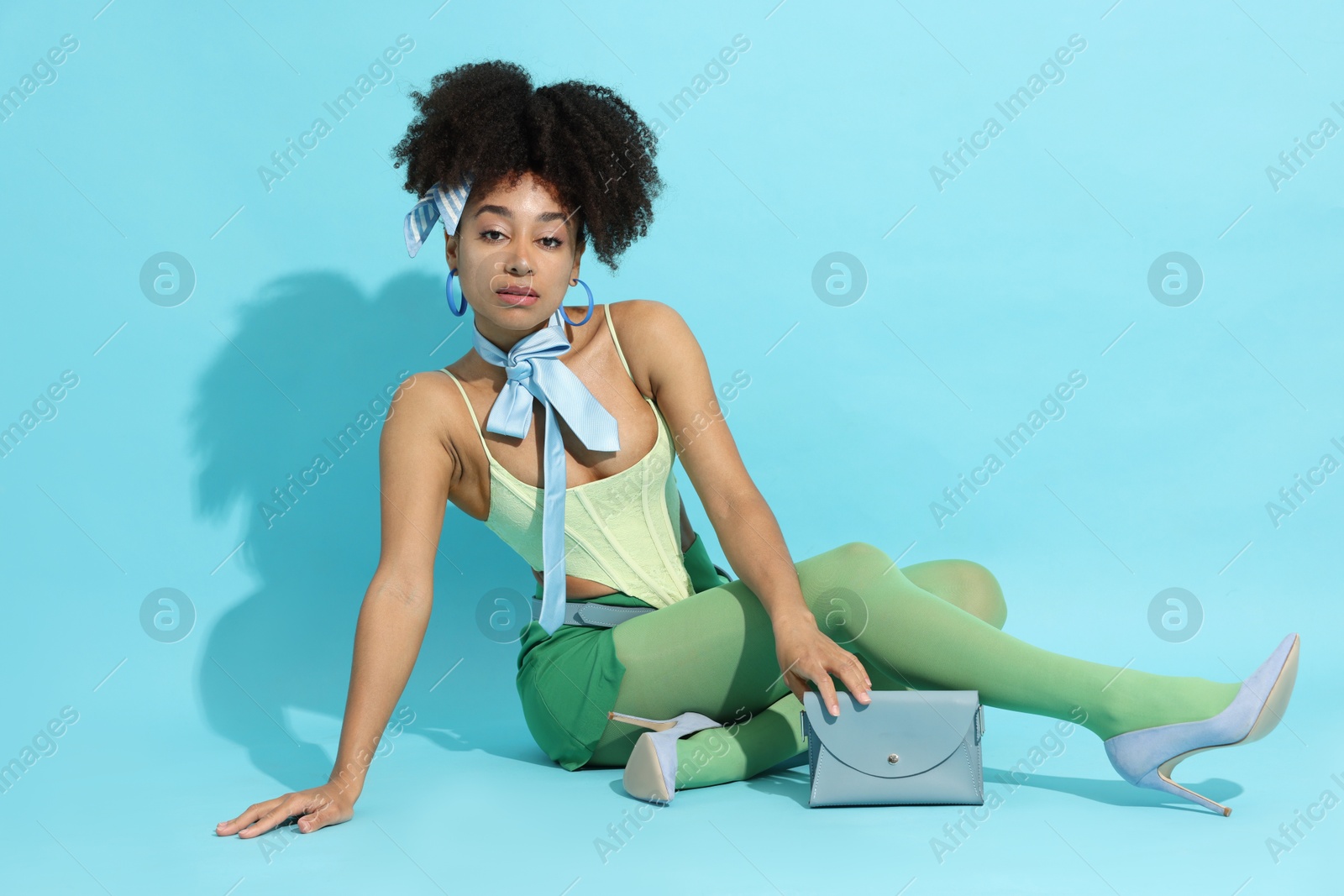 Fashionable portrait of beautiful Brazilian woman in stylish outfit on light blue background Photo of Fashionable portrait of beautiful Brazilian woman in stylish outfit on light blue background
