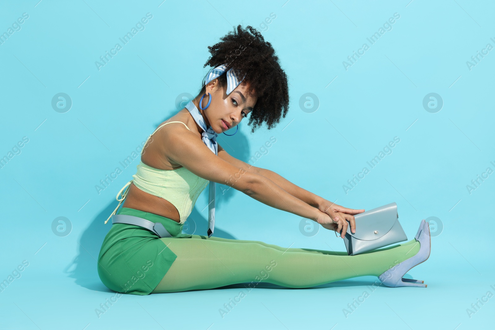 Fashionable portrait of beautiful Brazilian woman in stylish outfit on light blue background Photo of Fashionable portrait of beautiful Brazilian woman in stylish outfit on light blue background