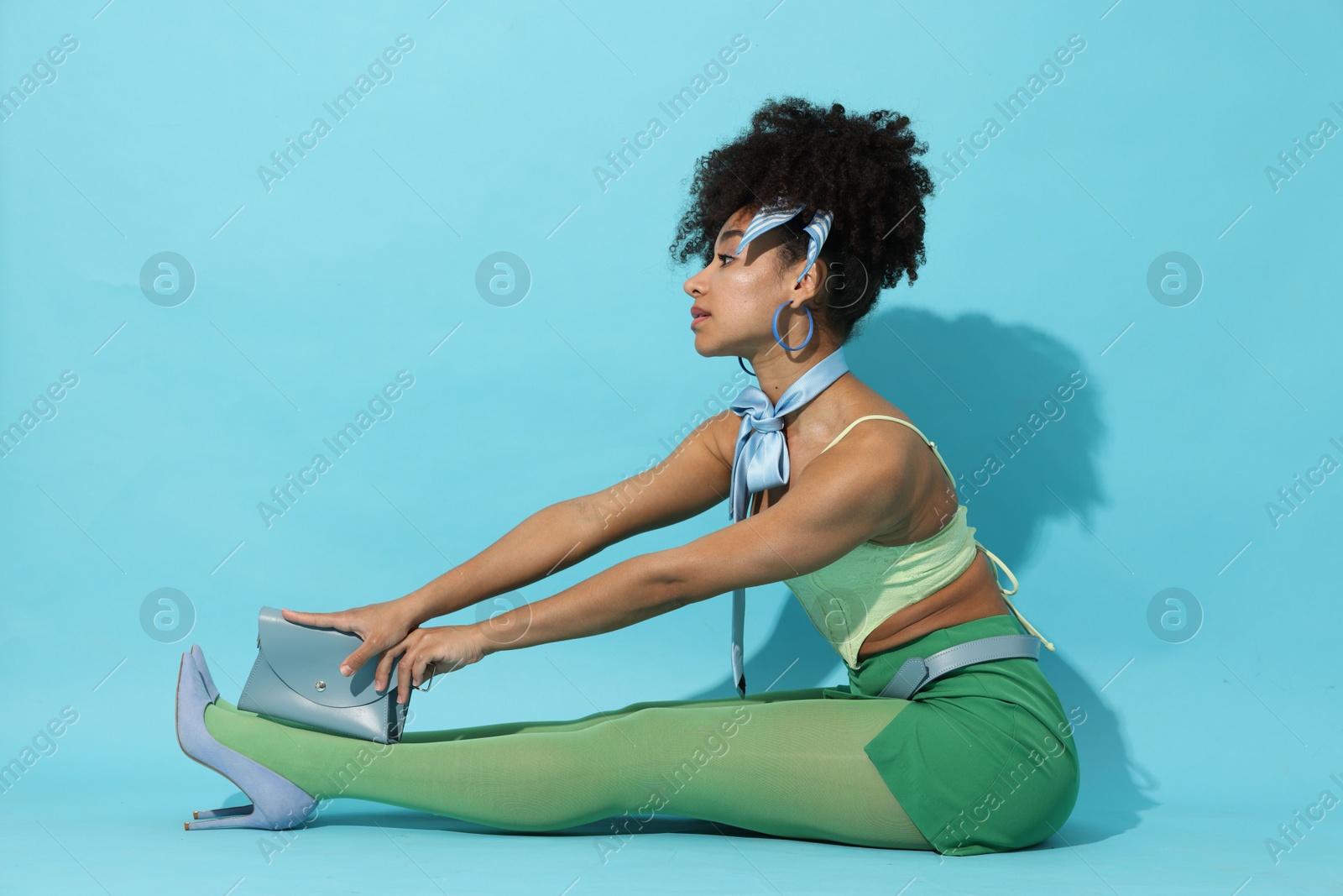 Fashionable portrait of beautiful Brazilian woman in stylish outfit on light blue background Photo of Fashionable portrait of beautiful Brazilian woman in stylish outfit on light blue background