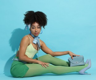 Photo of Fashionable portrait of beautiful Brazilian woman in stylish outfit on light blue background
