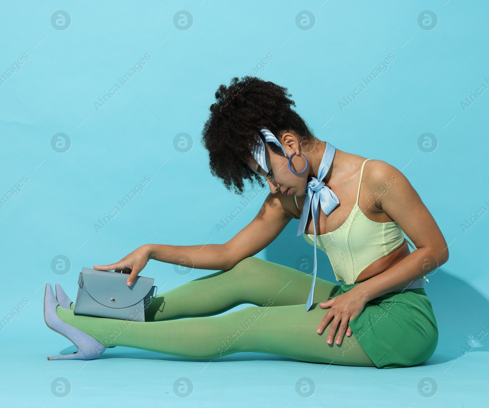 Fashionable portrait of beautiful Brazilian woman in stylish outfit on light blue background Photo of Fashionable portrait of beautiful Brazilian woman in stylish outfit on light blue background