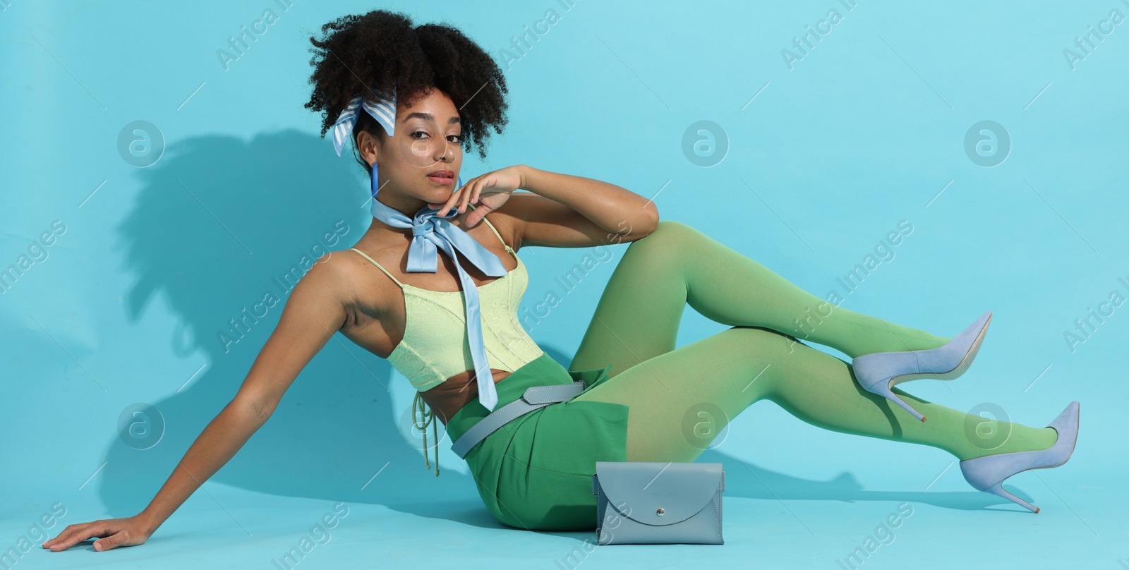 Fashionable portrait of beautiful Brazilian woman in stylish outfit on light blue background Photo of Fashionable portrait of beautiful Brazilian woman in stylish outfit on light blue background