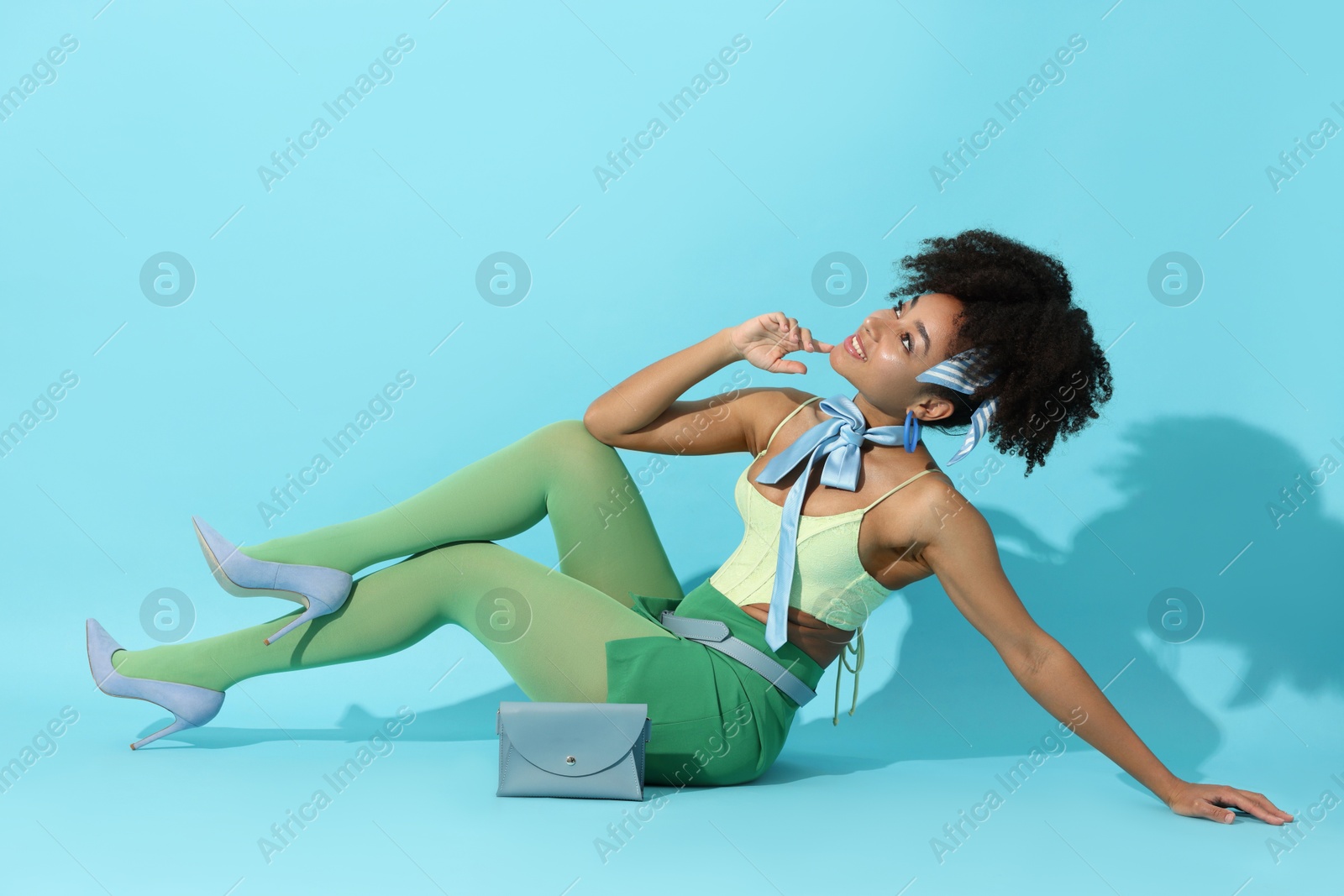 Fashionable portrait of beautiful Brazilian woman in stylish outfit on light blue background Photo of Fashionable portrait of beautiful Brazilian woman in stylish outfit on light blue background